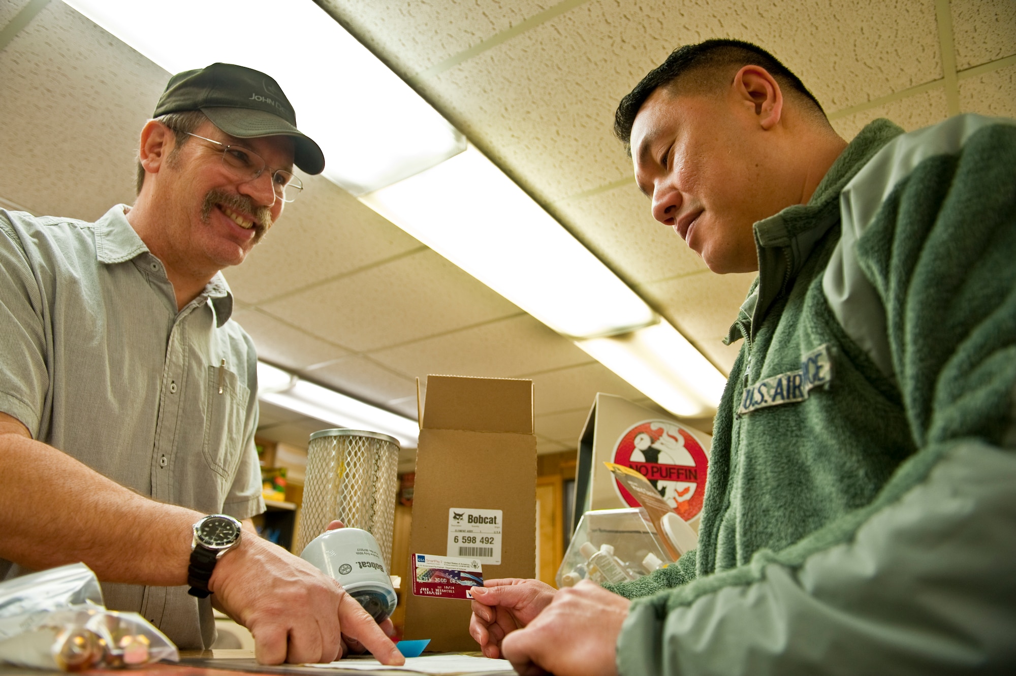 Air Force Tech. Sgt. Oliver Lucero, right, purchases a valve stem, lug nuts, an air filter and an engine oil filter from Tom Parsons at an auto vendor in Anchorage, Alaska January 10, 2012. The seemingly common parts are hard to find at some locations like Deigo Garcia, so they are obtained through Joint Base Elmendorf-Richardson's 673d Vehicle Parts Supply Organization, a part of the Vehicle Management Flight. Lucero is the Noncommissioned Officer in Charge of VPSO. Parsons retired from vehicle maintenance in the Air Force in 2004 and since then has worked as a parts technician where he works regularly with JBER’s VPSO office. The VPSO office specializes in obtaining ground vehicle parts for PACAF bases that don’t otherwise have access. (U.S. Air Force photo/Staff Sgt. Robert Barnett)