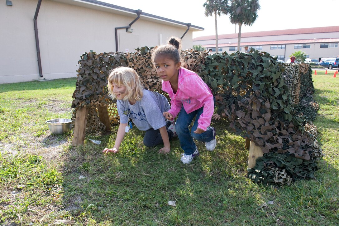 Two girls run from beneath camouflage netting as part of a children’s obstacle course,
new for this year’s Kids Understanding Deployment Operations. More than 70 children participated in the second Patrick KUDOS to gain a better understanding of deployments in a fun and incteractive environment. (U.S. Air Force photo/Julie Dayringer)