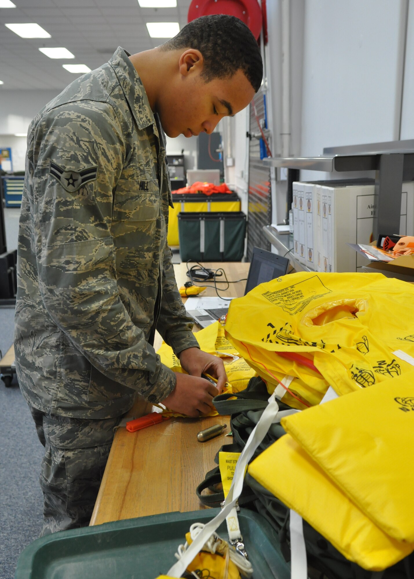 Airman 1st Class Christian Hill, 62nd Operations Support Squadron aircrew flight equipment technician, installs sail protectors onto life preservers Jan. 11, 2012, at Joint Base Lewis-McChord, Wash. The equipment prevents the life vests from inflating without warning. (U.S. Air Force photo/Airman 1st Class Leah Young)