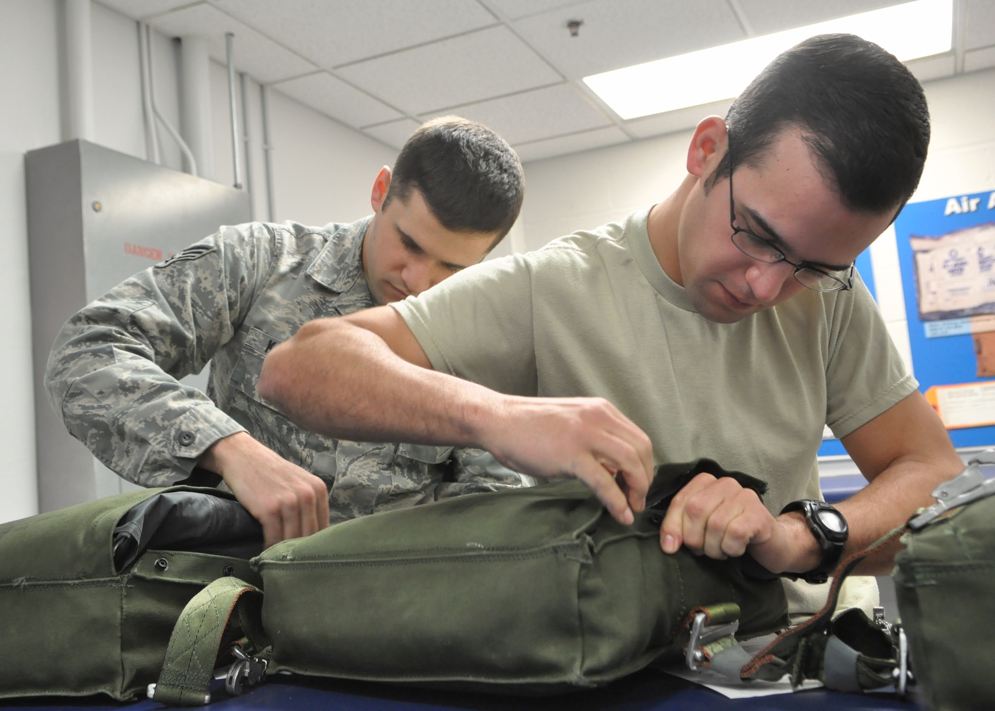 Airman 1st Class Anthony Carvalho, right, and Senior Airman Ryan Karcher, both 62nd Operations Support Squadron aircrew flight equipment technicians, prepare ML-4 packs Jan. 11, 2012, at Joint Base Lewis-McChord, Wash. These packs are one-man life rafts which attach to parachutes and are used in case of aircrew emergency. (U.S. Air Force photo/Airman 1st Class Leah Young)