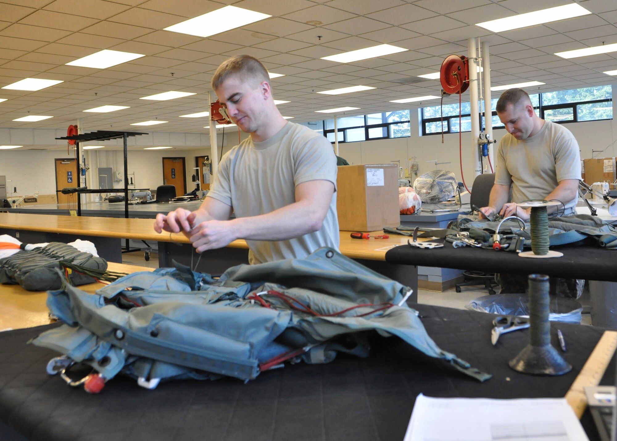 Senior Airman David Pondel, left, and Staff Sgt. Daniel Sifrar, both 62nd Operations Support Squadron aircrew flight equipment technicians, rig parachutes as part of their daily tasks Jan. 11, 2012, at Joint Base Lewis-McChord, Wash. As part of the 62nd OSS, the aircrew flight equipment flight is responsible for maximizing each aircrew member's performance by ensuring all products are current and safe when used to protect and sustain human life during flight operations. (U.S. Air Force photo/Airman 1st Class Leah Young)