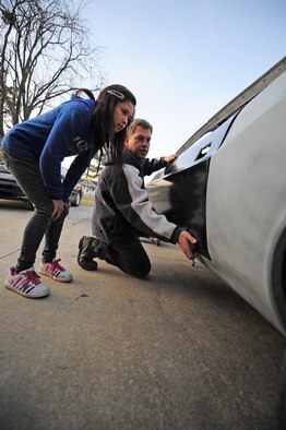 Master Sgt. Marty Stanton shows his daughter Alicia, 12, what the gap behind the door should look like before placing it on a 1974 Dodge Challenger at their home in Goldsboro, N.C., Jan. 5, 2012. Alicia helps her father with most of the body work on the cars he restores. Stanton is a 4th Logistics Readiness Squadron vehicle management superintendent. (U.S. Air Force photo by Senior Airman Rae Perry)