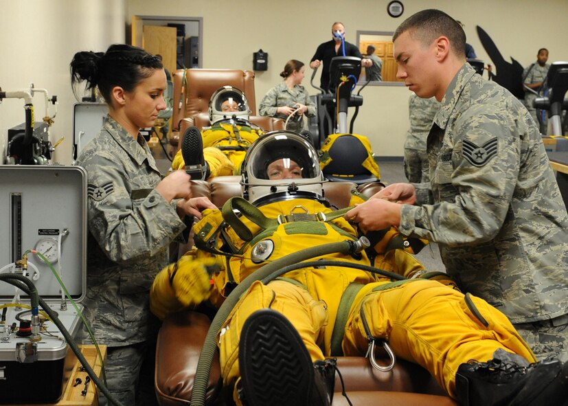 A U-2 Dragon Lady pilot and acoompanying passenger prepare for flight, while physiological support technicians, attach a parachute torso harness. (U.S. Air Force photo by John Schwab)