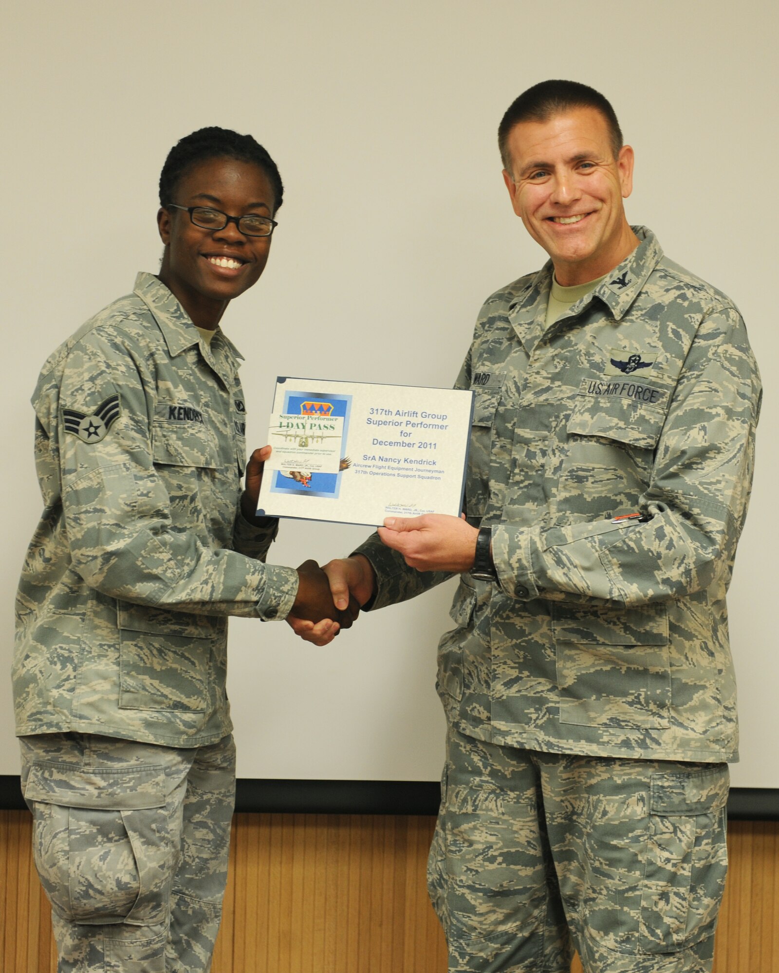 Col. Walter Ward, 317th Airlift Group commander, presents Senior Airman Nancy Kendrick, with the January 317 AG superior performer award, Jan. 12, 2012, at Dyess Air Force Base, Texas. Every month each group selects one person or team who has shown superior performance to be recognized in front of wing leadership. (U.S. Air Force photo by Airman 1st Class Cierra Bullock/Released) 