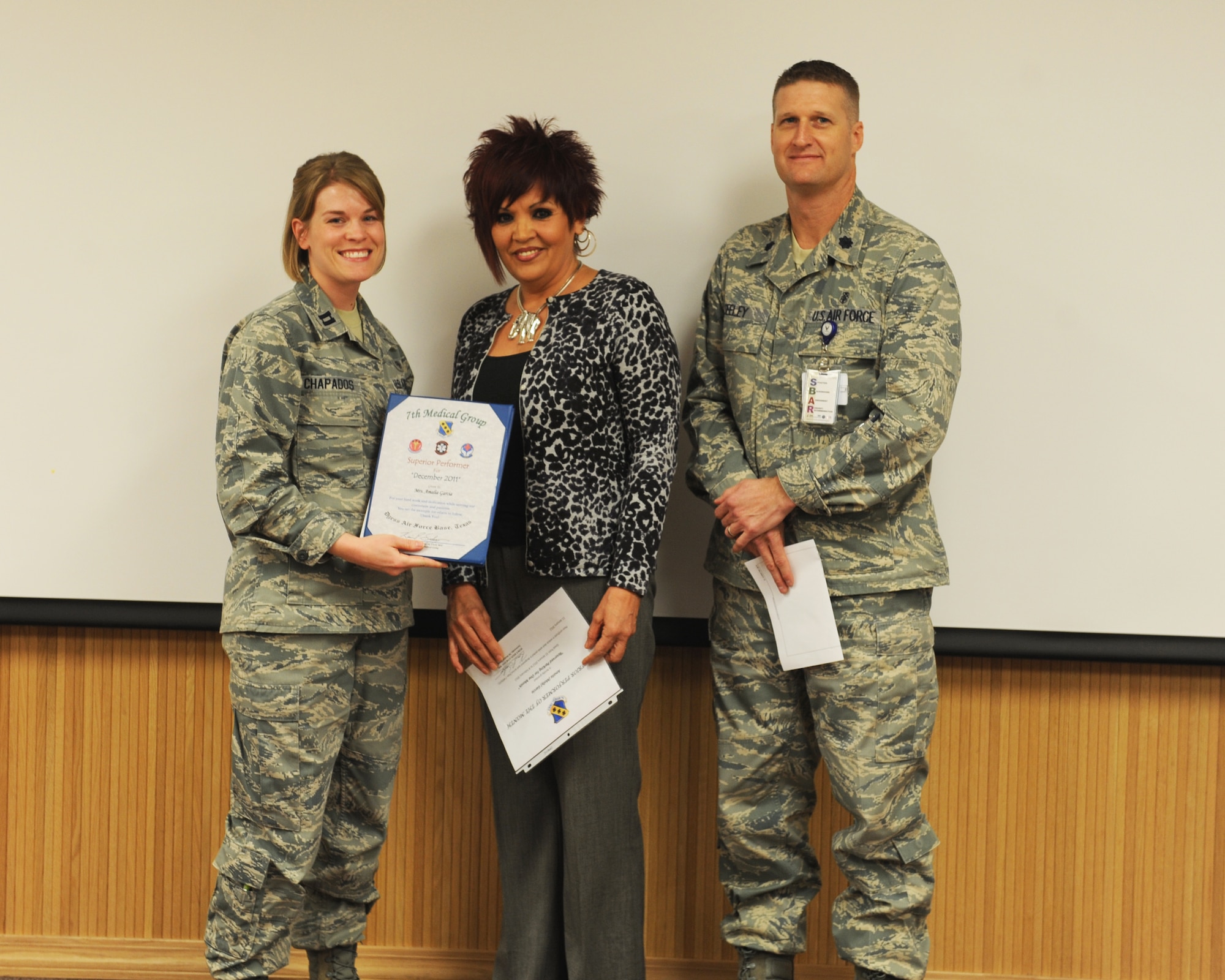 Capt. Kelsey Chapados, 7th Medical Group, left, and Lt. Col. Kevin Seeley, 7 MDG, right, presents Amalia Garcia, 7 MDG, center, with the January 7 MDG superior performer award, Jan. 12, 2012, at Dyess Air Force Base, Texas. Every month each group selects one person or team who has shown superior performance to be recognized in front of wing leadership. (U.S. Air Force photo by Airman 1st Class Cierra Bullock/Released) 
