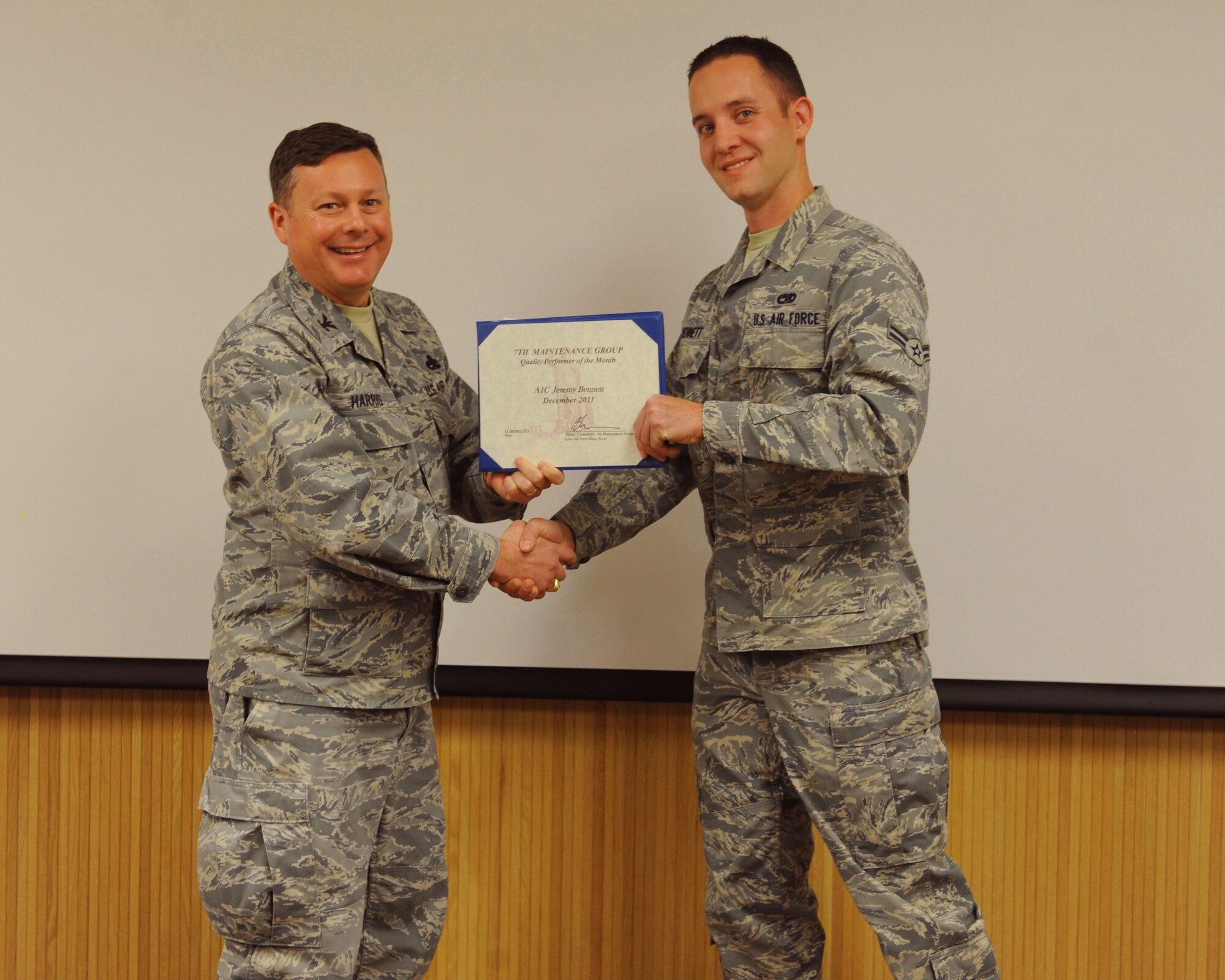 Col. Bryan Harris, 7th Maintenance Group deputy commander, presents Airman 1st Class Jeremy Bennett, 7 MXG, with the January 7 MXG superior performer award, Jan. 12, 2012, at Dyess Air Force Base, Texas. Every month each group selects one person or team who has shown superior performance to be recognized in front of wing leadership. (U.S. Air Force photo by Airman 1st Class Cierra Bullock/Released) 