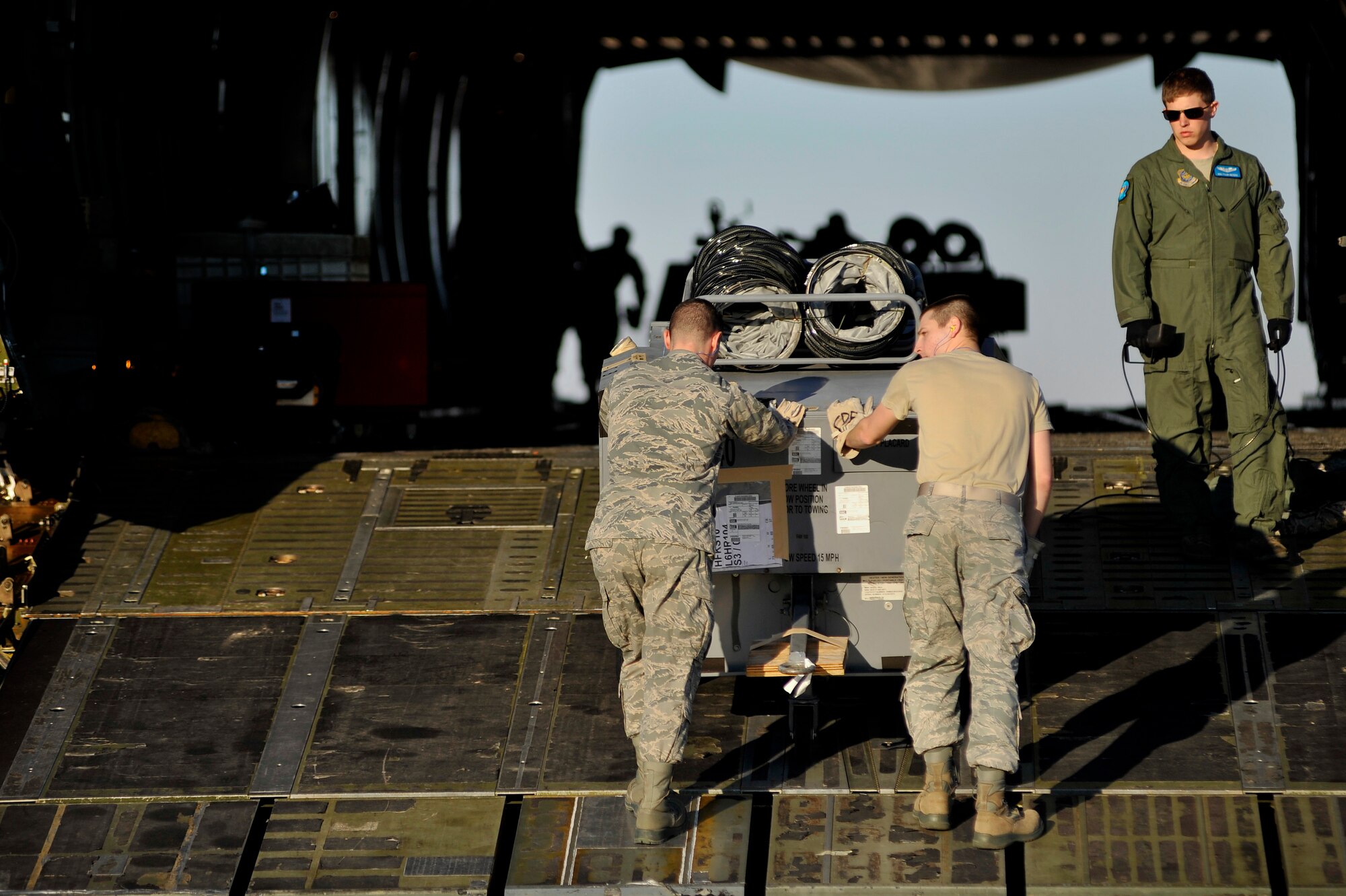 U.S. Air Force Senior Airman Brad Prouty, 20th Communications Squadron and Senior Airman Justen Knighten, 20th Logistics Readiness Squadron, load aerospace ground equipment onto a C-5 Galaxy aircraft, Jan. 6, 2012. Three C-5s landed at Shaw over a three day period to pick up Airmen and supplies in support of a deployment tasking being filled by Shaw Airmen. (U.S. Air Force Photo by Senior Airman Kenny Holston/Released)


