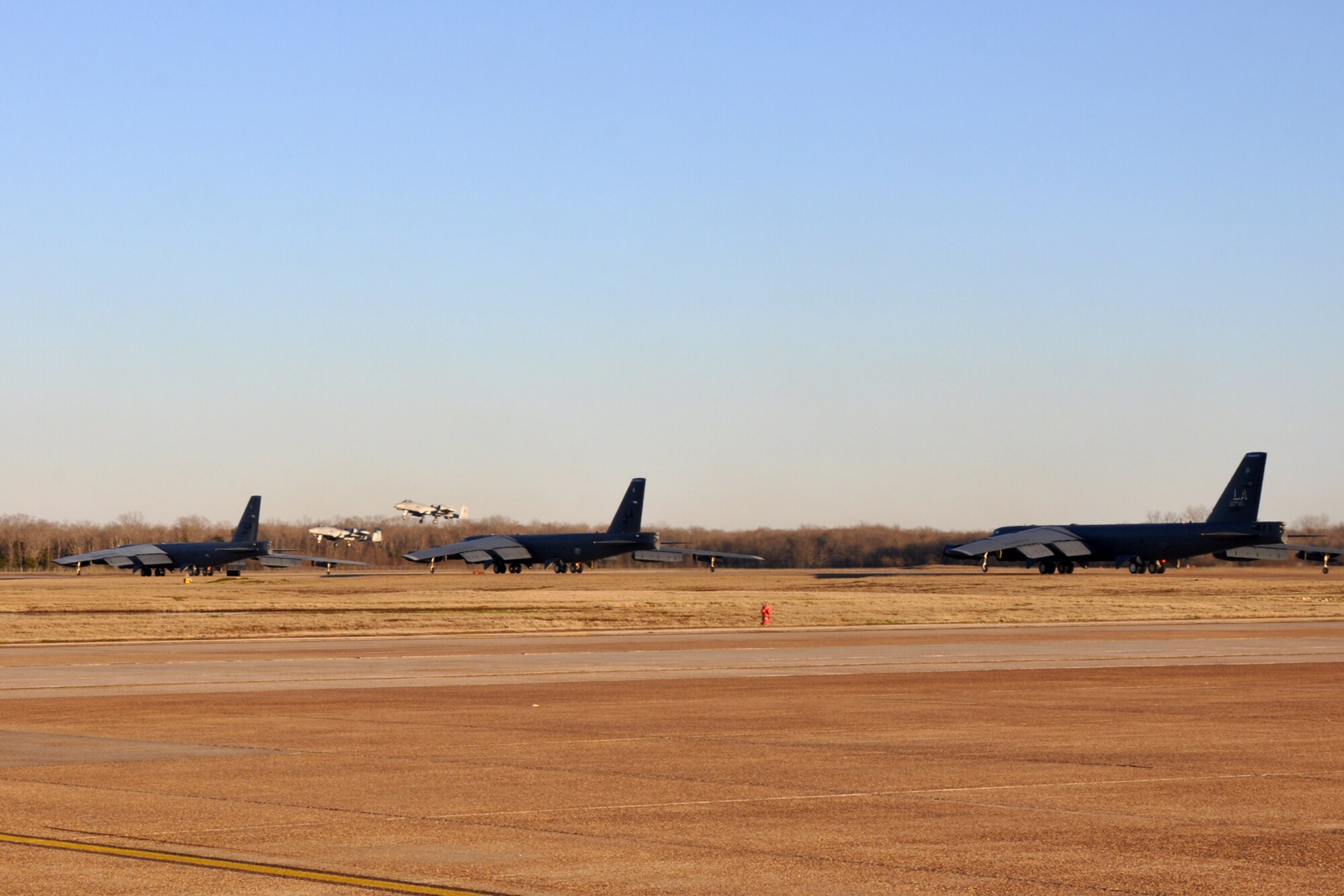 Three B-52 Stratofortresses assigned to the 2nd Bomb Wing wait their turn on a busy runway as two A-10 Thunderbolt IIs from the 917th Fighter Group make their approach at Barksdale Air Force base, La., Jan. 11, 2012. One of the A-10s landed while the other peeled off and landed later. U.S Air Force photo by Master Sgt. Jeff Walston)