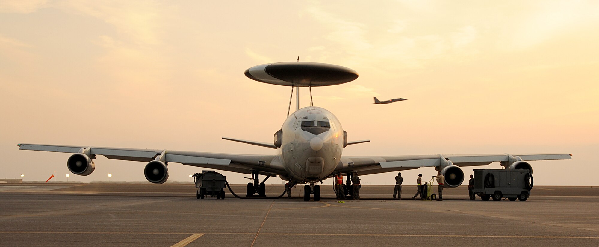 Maintenance Airmen prepare an E-3 Sentry airborne warning and control systems aircraft for takeoff while an F-15C Eagle flies by Jan. 5, 2012. The E-3 is deployed to the 380th Air Expeditionary Wing from Tinker Air Force Base, Okla. An E-3 crew from Kadena Air Base, Japan, coordinated the rescue of a crashed AH-64 Apache helicopter crew in Afghanistan Dec. 30, 2011. (U.S. Air Force photo/Tech. Sgt. Arian Nead)