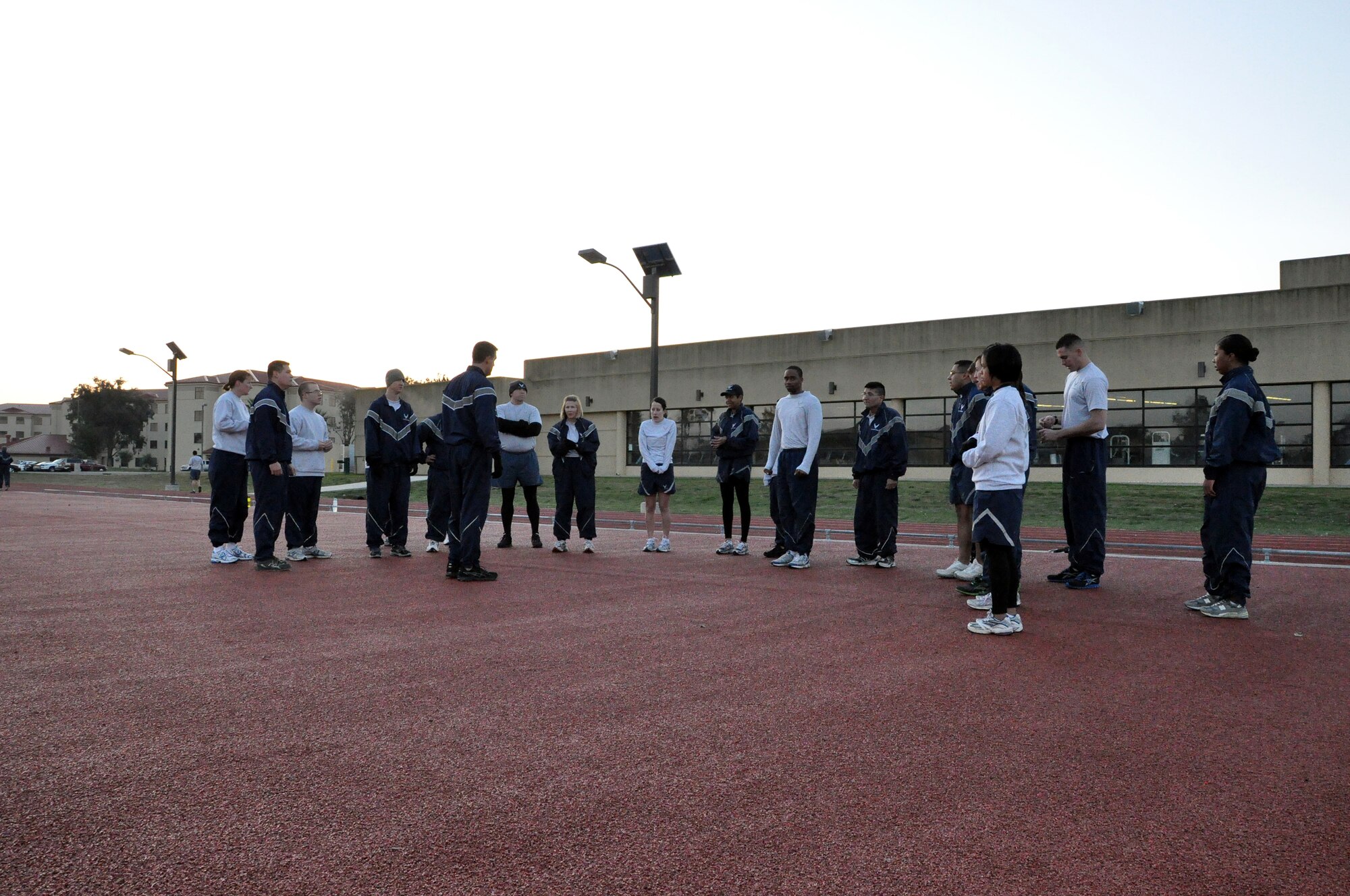 Members of the 60th Force Support Squadron huddle together Monday. The 14,500-square-foot pad is made of the same rubberized surface as the base's track.
