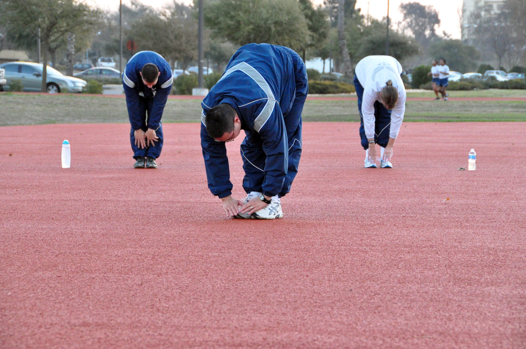 Tech. Sgt. Franklin Guerro, center, 60th Force Support Squadron, leads his squadron in physical training Monday at the new fitness psd behind the Travis Fitness Center. The pad was installed as an improvement over muddy field conditions in the grass in the center of the facility's track, said Dean Fazzio, director of the fitness center. 