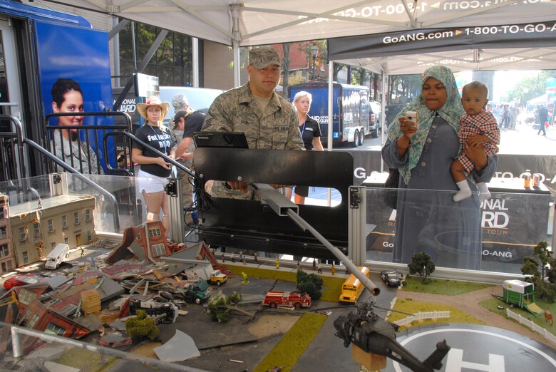 Master Sgt. Andy Raup, 111th Fighter Wing Recruiting Office Supervisor, demonstrates disaster response movements to a mother and child visiting the
Air National Guard “Rise to the Challenge” recruiting trailer display area Sept. 9, 2011.  Raup and military members participated in a special edition of "Good
Day Philadelphia" that paid tribute to armed forces serving our country locally and abroad. The event was first held in November (to align with Veterans Day), but was moved this year to commorate the ten year anniversary of 9/11.