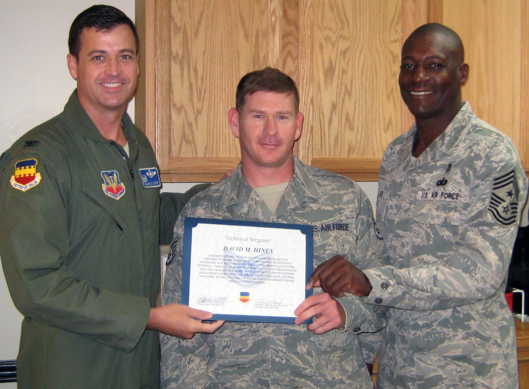 Col. Charlie Moore, 20th Fighter Wing commander, and Chief Master Sgt. Lefford Fate, 20th FW command chief, hand technical sergeant stripes to Staff Sgt. David Hines, 20th Civil Engineer Squadron vertical repair shop, in a STEP promotion, Dec. 20, 2011, Shaw Air Force Base, S.C. The Stripes for Exceptional Performers program recognizes outstanding individuals by instantly promoting them to staff, technical or master sergeant. (Courtesy Photo)