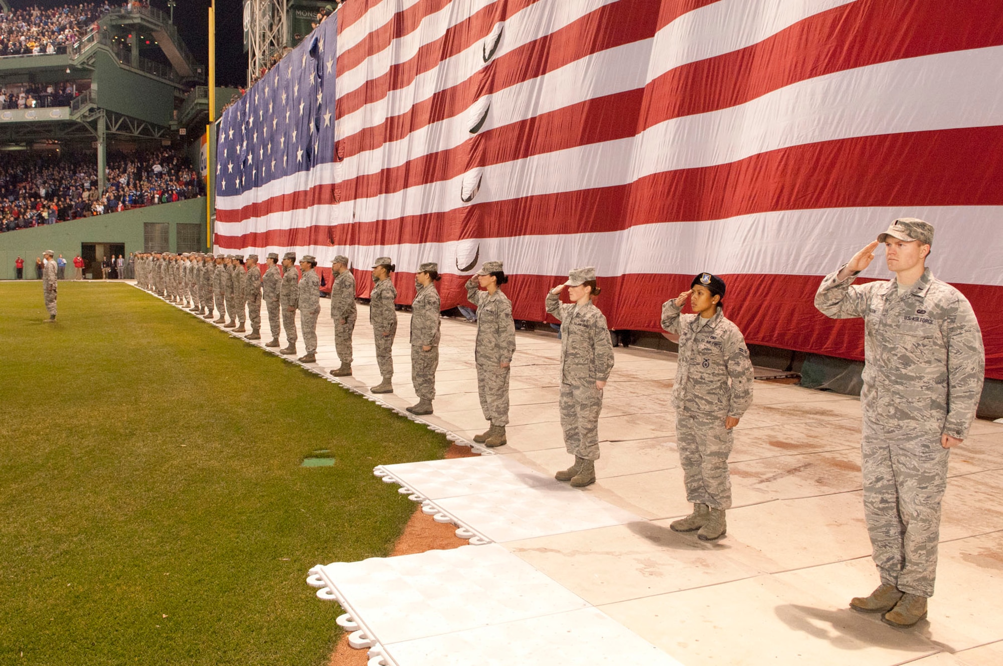 BOSTON – Airmen from Hanscom Air Force Base salute in front of the flag during the national anthem at the Frozen Fenway college hockey game at Fenway Park on Jan. 7. After the national anthem, Airmen enjoyed the game between Maine and New Hampshire. (U.S. Air Force photo by Mark Wyatt)