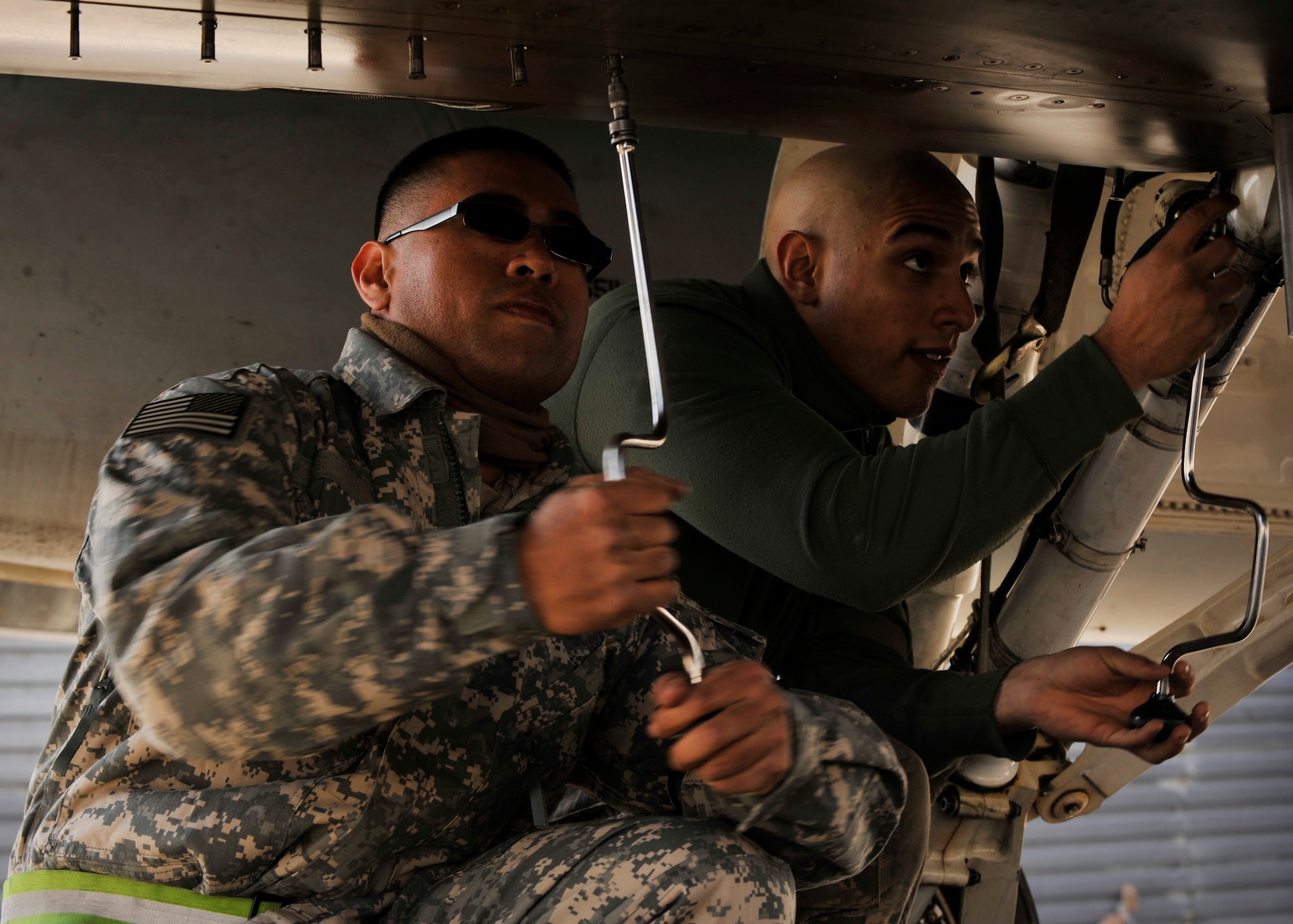 BAGRAM AIRFIELD, Afghanistan-- Airman 1st Class Jonathan Nieves and Staff Sgt. Carlo Lat open a panel on an F-16 Aircraft at Bagram Airfield, Afghanistan. Nieves is an aircraft electrician with the 16th Aircraft Maintenance Unit. Lat is a crew chief with the 16th Aircraft Maintenance Unit.  Both are deployed from the 177th Fighter Wing, NJ. (U.S. Air Force photo/Airman 1st Class Ericka Engblom)