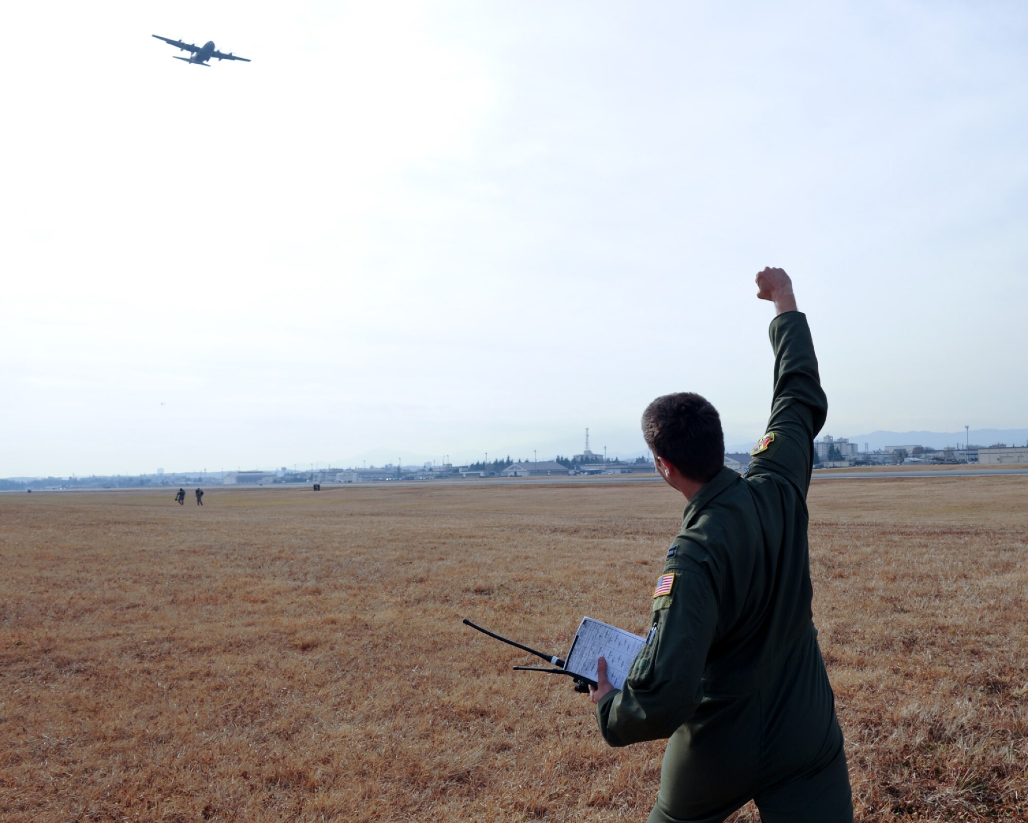 YOKOTA AIR BASE, Japan -- Capt. Dereck Monnier, a C-130 Hercules co-pilot with the 36th Airlift Squadron, celebrates as a 36th AS C-130 flies overhead during a Samurai Surge formation flight at Yokota Air Base, Japan, Jan. 10, 2012. Monnier supported the mission as a drop zone control officer, ensuring safe airdrop training operations at Yokota's airfield. (U.S. Air Force photo/Capt. Raymond Geoffroy)