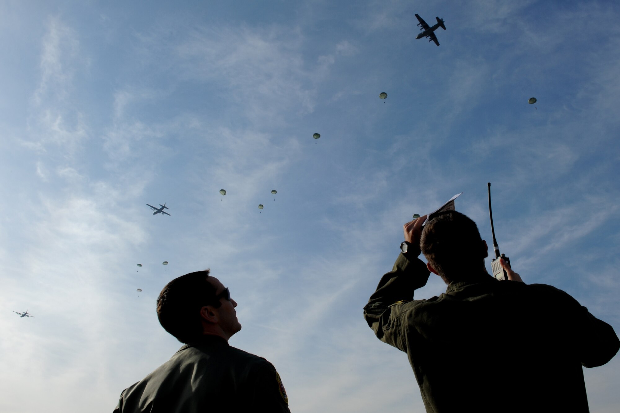 YOKOTA AIR BASE, Japan -- Capt. Dereck Monnier (right) and 1st Lt. Tory Lodmell, both C-130 Hercules co-pilots with the 36th Airlift Squadron, observe as U.S. Army paratroopers descend onto the airfield during a Samurai Surge formation flight at Yokota Air Base, Japan, Jan. 10, 2012. The Airmen supported the mission as drop zone control officers, ensuring safe airdrop training operations at Yokota's airfield. (U.S. Air Force photo/Capt. Raymond Geoffroy)