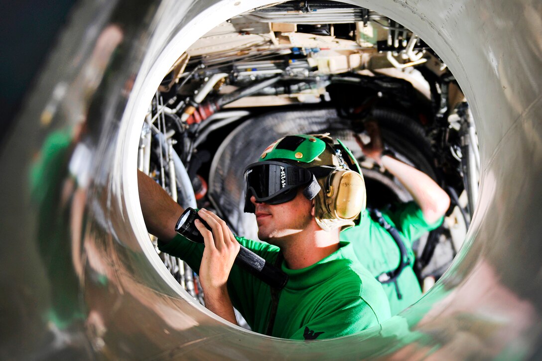 U.S. Navy Petty Officer 3rd Class Charles Follet cleans the engine bay of an EA-6B Prowler in the hangar bay aboard the aircraft carrier USS Carl Vinson in the Indian Ocean, Jan. 7, 2012. Follet, an aviation electrician's mate, is assigned to Electronic Attack Squadron 134.