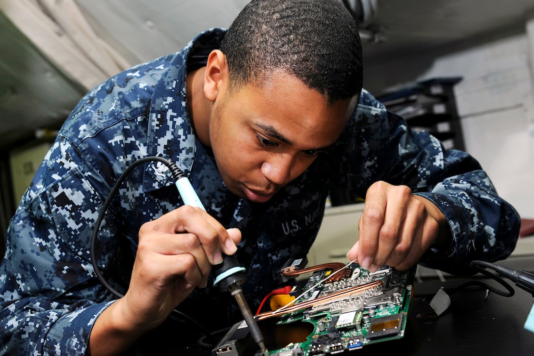 U.S. Navy Petty Officer 3rd Class Rowdy Rasmus solders computer equipment aboard the aircraft carrier USS Carl Vinson in the Indian Ocean, Jan. 10, 2012. Rasmus, an interior communications electrician, is assigned to the air department.