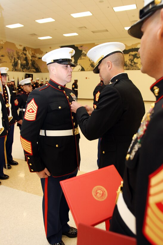 Maj. Richard Robinson, III, commanding officer, Marine Corps Recruiting Station Oklahoma City (center), pins the Meritorious Service Medal on the chest of Sgt. Maj. Bruce Cowperthwaite for his honorable service as sergeant major of RS Oklahoma City from April 2009 to January 2012, during his post and relief ceremony at the Armed Forces Training Center in Mustang, Okla., Jan. 13. Cowperthwaite was also retired upon his relief as sergeant major Okla. City after 21 years of service to the Corps.