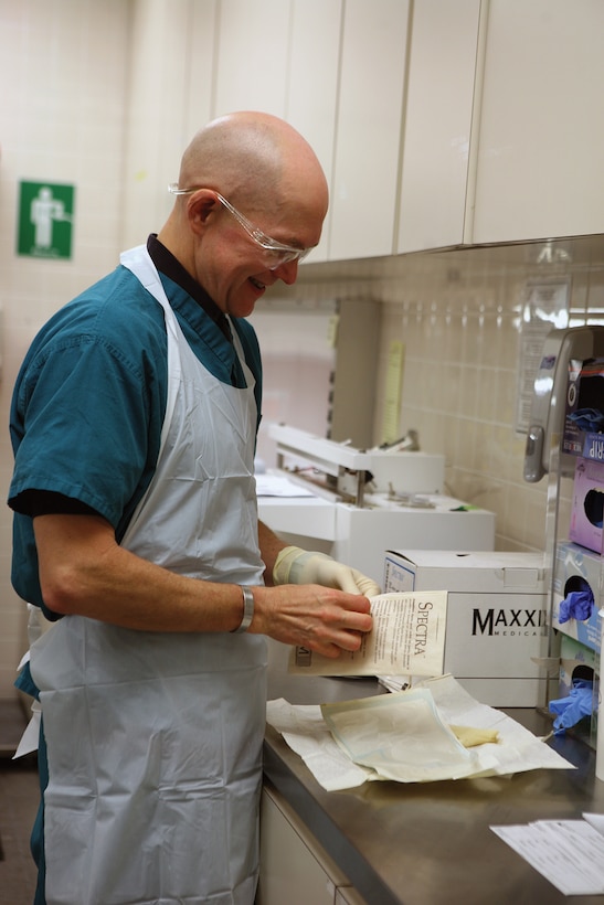 Navy Cmdr. Edward A. Reedy, the staff pathologist and the director of clinical support services at U.S. Naval Hospital Okinawa, prepares to work on human tissue samples by putting on protective clothing here Jan. 13. Reedy is one of two armed forces medical examiners outside of the United States whose jurisdiction covers the Western Pacific including Hawaii, Republic of Korea, Japan and the Republic of the Philippines.
