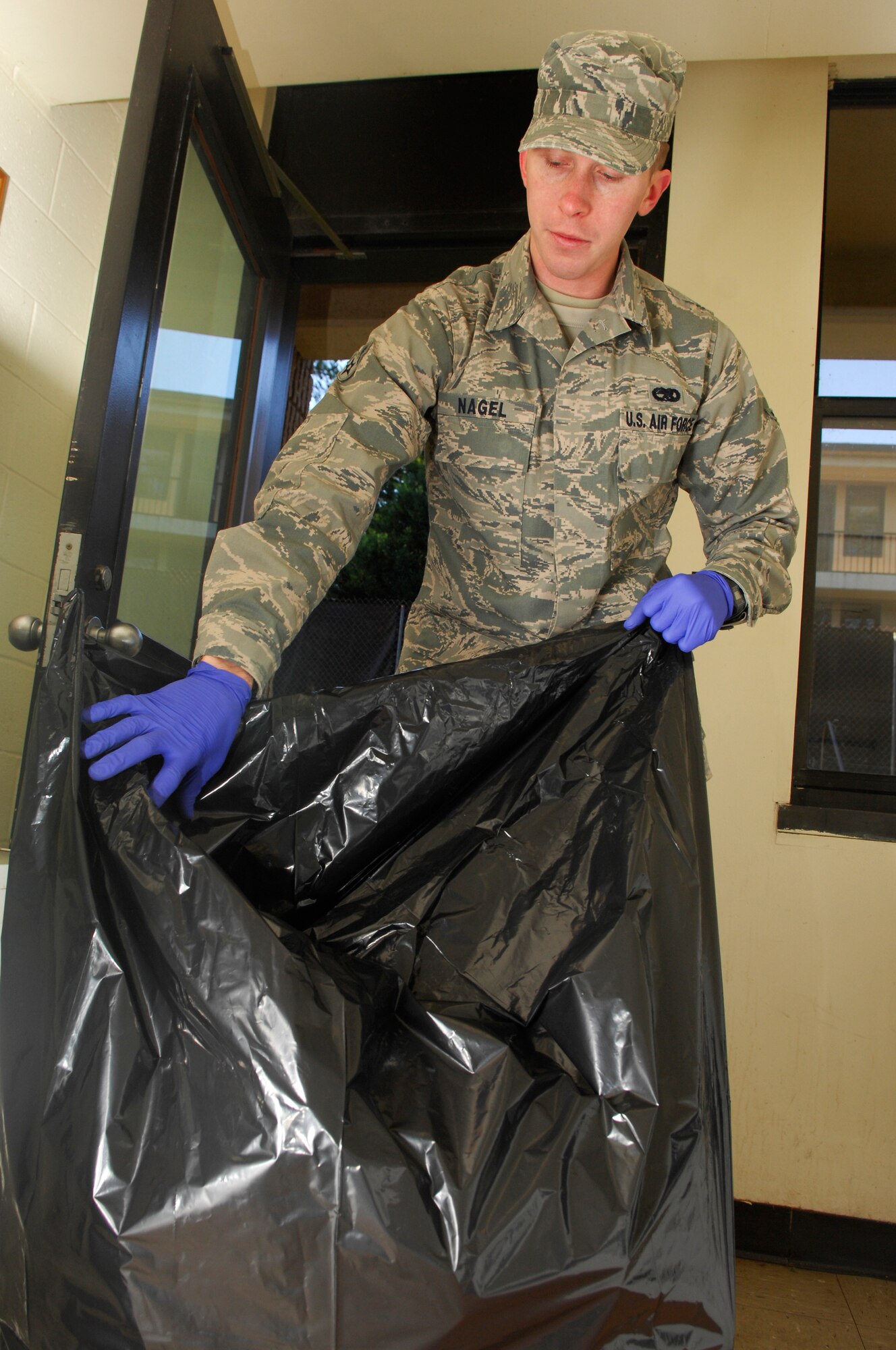 U.S. Air Force Airman Sean Nagel, 20th Aircraft Maintenance Squadron, takes out the trash in the laundry area of the dormitory for bay orderly, Shaw Air Force Base, S.C., Jan.13, 2012. Bay orderly is a weeklong extra duty where dorm residents ensure their living quarters are clean and in inspection order. (U.S. Air Force photo by Airman 1st Class Ashley L. Gardner/Released)