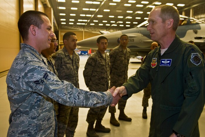 U.S. Air Force Gen. Mike Hostage, commander of Air Combat Command, greets Airman 1st Class David Agosto, 57th Aircraft Maintenance Squadron crew chief, Jan. 11, 2012, inside the Viper Aircraft Maintenance Unit hangar at Nellis Air Force Base, Nev. Hostage congratulated all the 57th AMXS Airmen for the excellent work they do. (U.S. Air Force photo by Senior Airman Brett Clashman/Released)