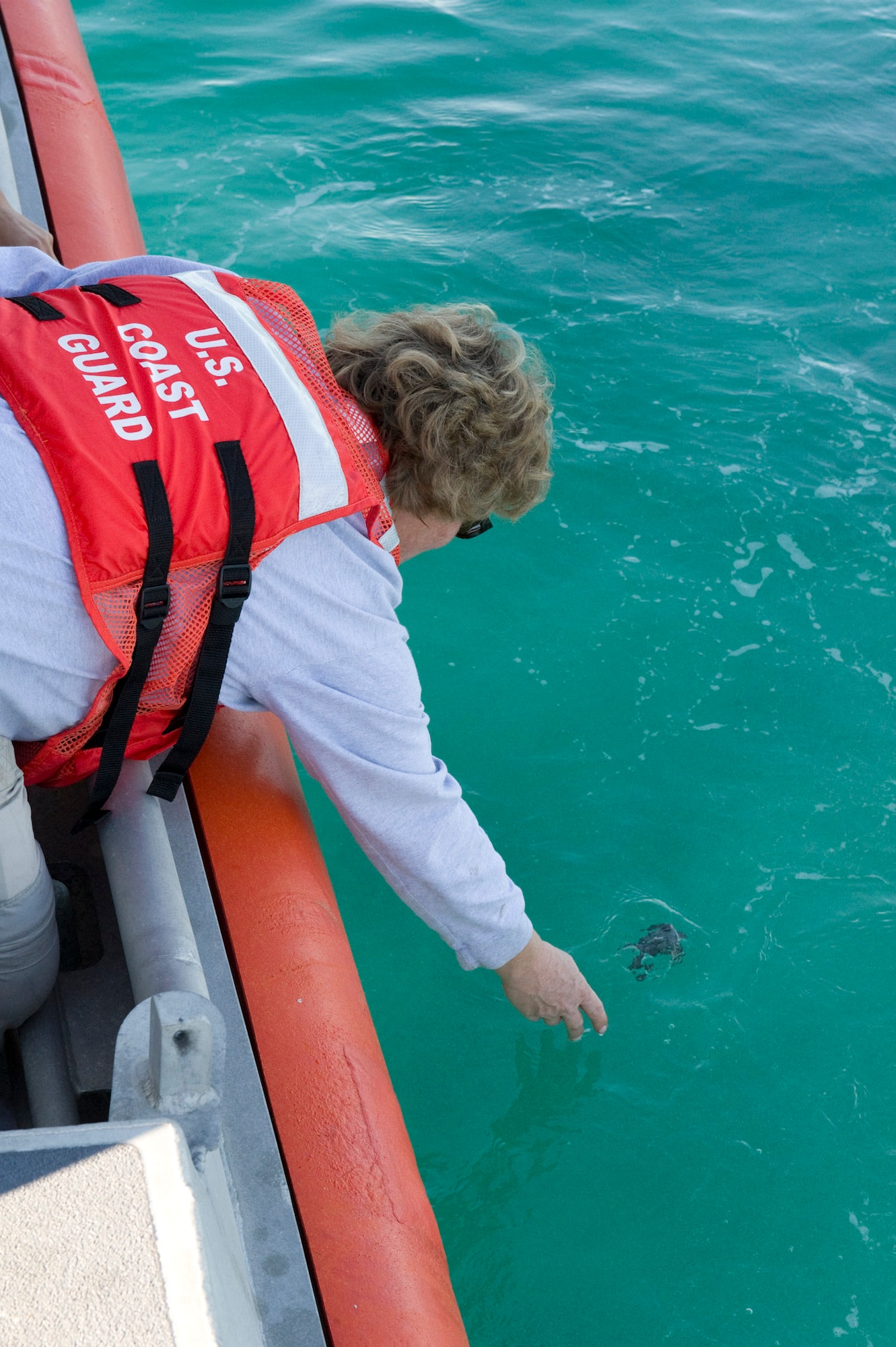Martha Carroll, a biologist with the 45th Civil Engineer Squadron Asset Management Flight, releases a Green sea turtle hatching into the ocean from the deck of a U.S. Coast Guard search and rescue boat 20 miles off shore. (Photo by Julie Dayringer)