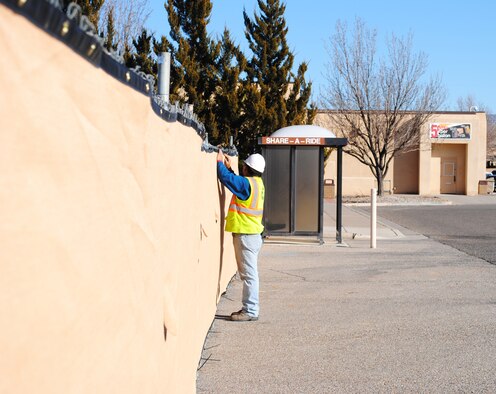 Leo Diaz of Scott’s Fencing ties down the fabric cover of the fence surrounding the construction site west of the Exchange building Jan. 6.  Photo by Christopher Bailey