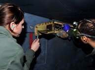 MINOT AIR FORCE BASE, N.D -- Airman Alyssa Mills, 5th Aircraft Maintenance Squadron aircraft weapon armament apprentice and Staff Sgt. Jesus Virola Martinez, 5th AMXS aircraft weapon armament craftsman, connect a grease gun to release the pylon on a B-52H Stratofortress during a munitions download operation here Jan. 11. Munitions downloads are performed monthly to ensure proficiency and certification of weapon specialists. (U.S. Air Force photo/Senior Airman Desiree W. Esposito)