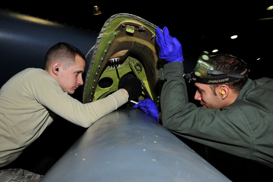 MINOT AIR FORCE BASE, N.D -- Staff Sgts. Christopher West and Jesus Virola Martinez, 5th Aircraft Maintenance Squadron aircraft weapon armament specialists, remove bolts holding the buffet fairing on a B-52H Stratofortress during a munitions download operation here Jan. 11. Munitions downloads are performed monthly to ensure proficiency and certification of weapon specialists. (U.S. Air Force photo/Senior Airman Desiree W. Esposito)