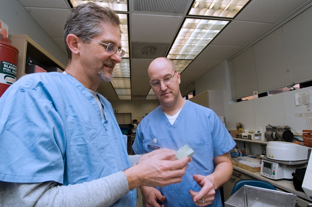 Retired Lt. Col. Martin Yules, 779th Dental Squadron prosthodontist , left, and Lt. Col. Philip Junghans, 779 DS flight commander, examine a bite plate appliance in the Andrews dental laboratory Jan. 10. The bite plate is used to protect teeth from night time grinding. (Photo /Bobby Jones)