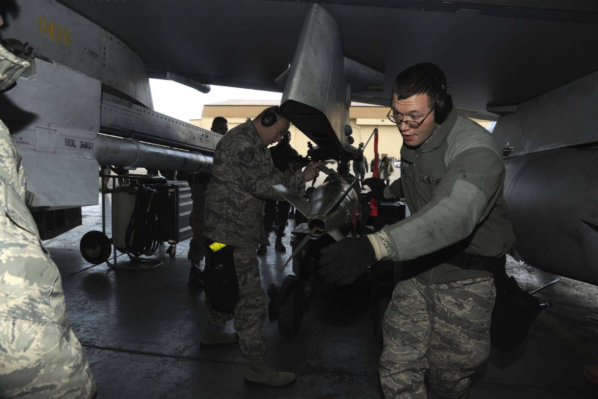 Senior Airman Lucas Wolf, Aircraft Maintenance Unit weapons load crew member, watches a weapon being lined up to be loaded under the wing of a F-16 Fighting Falcon during a peninsula weapons loading competition at Kunsan Air Base, Republic of Korea, Jan. 11, 2012. Each team raced against time loading training weapons on their respective F-16 Fighting Falcons trying to minimize discrepancies. The training of the teams improves job performance, but it also fosters teamwork and camaraderie. (U.S. Air Force photo by Staff Sgt. Rasheen A. Douglas/Released)