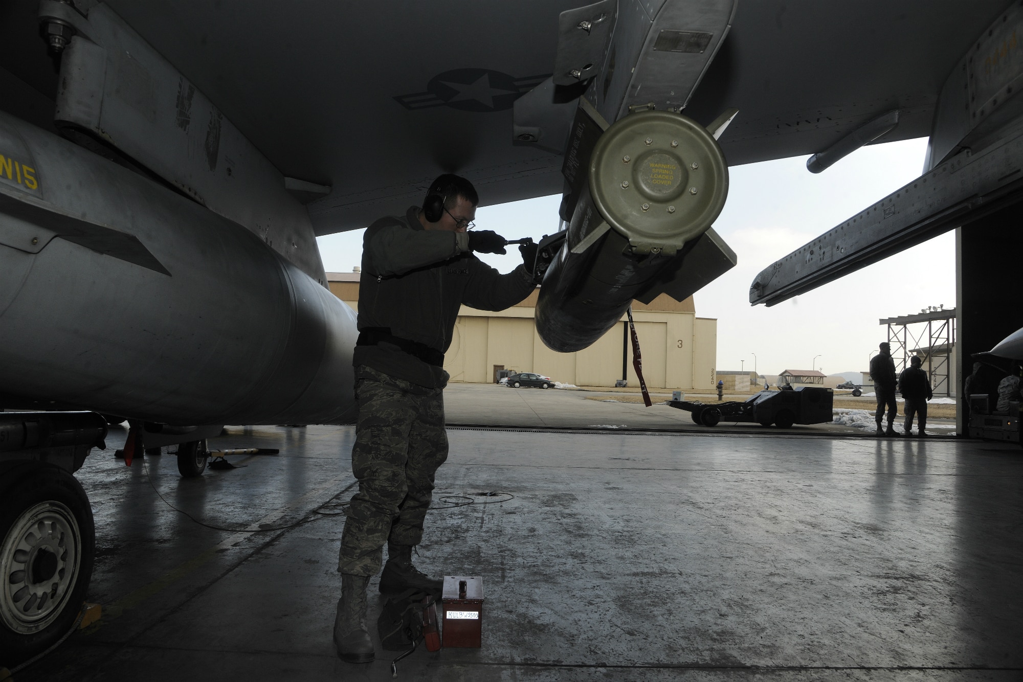 Senior Airman Lucas Wolf, 80th Aircraft Maintenance Unit weapons load crew member, makes sure a weapon is securely placed on the wing of an F-16 Fighting Falcon during a peninsula weapons loading competition at Kunsan Air Base, Republic of Korea, Jan. 11, 2012. Each team raced against time loading training weapons on their respective F-16 Fighting Falcons trying to minimize discrepancies. The training of the teams improves job performance, but it also fosters teamwork and camaraderie. (U.S. Air Force photo by Staff Sgt. Rasheen A. Douglas/Released)