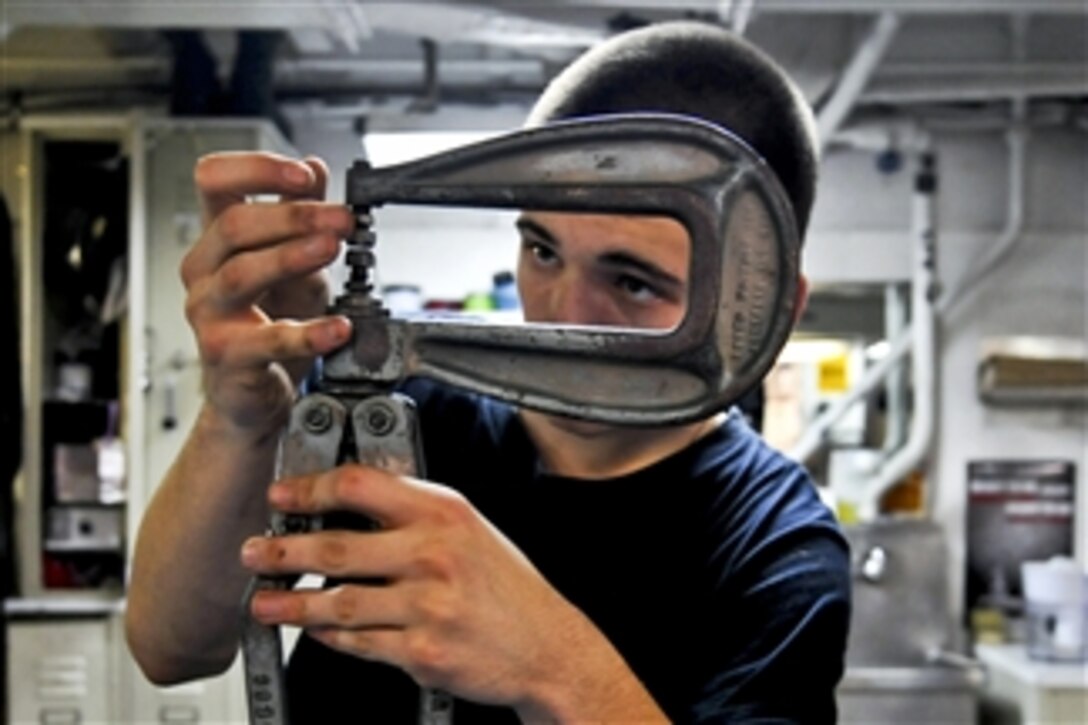 U.S. Navy Seaman Kaleb White adjusts a rivet squeezer while repairing a damage bucket aboard the aircraft carrier USS Carl Vinson (CVN 70) in the Indian Ocean on Jan. 10, 2012.  White is assigned to the aircraft intermediate maintenance department.  