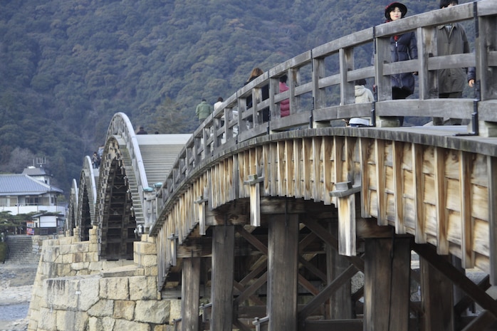 Visitors walk across the Kintai Bridge in Iwakuni, Jan. 14. The Kintai Bridge, Iwakuni’s most iconic symbol, gives all those willing to pay a small fee the chance to walk across its::r::::n::ancient design. The original bridge was finished Oct. 1, 1673. The bridge that was reconstructed in 1953 undergoes repair on regular intervals to maintain the integrity of the bridge.