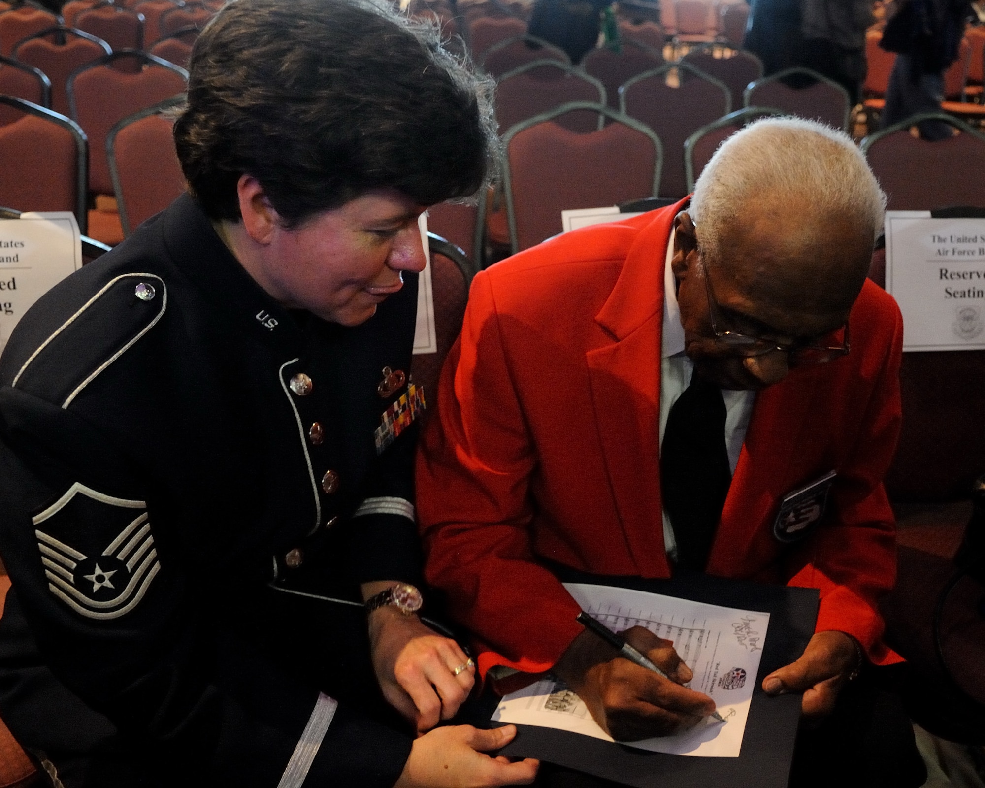 Retired U.S. Air Force Chief Master Sgt. Richard R. Hall, Jr., a member of the Tuskegee Airmen, signs a score sheet for U.S. Air Force Master Sgt. Tara Islas, a U.S. Air Force Band Ceremonial Brass french hornist and native of Mobile, Ala., following a concert at The First Academy Faith Hall in Orlando, Fla., Jan. 14, 2011.  The U.S. Air Force Band Ceremonial Brass honored Tuskegee Airmen, the first African American military aviators in the U.S. armed forces, during their performance, playing a new work entitle "Red Tail Skirmish."  U.S. Air Force photo by Master Sgt. Adam M. Stump/Released.