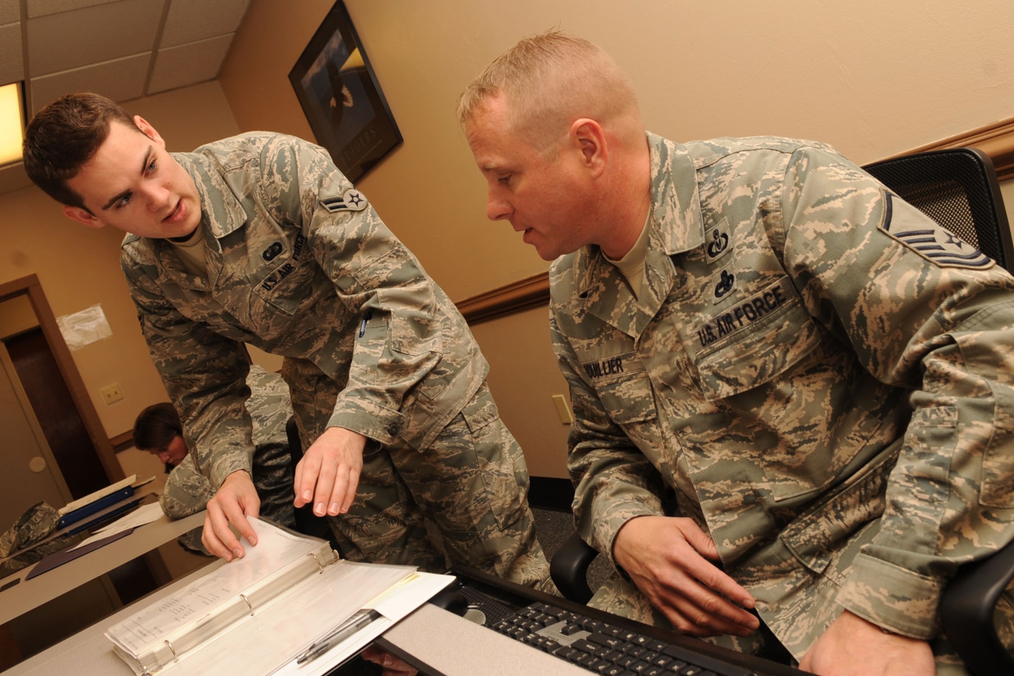 U. S. Air Force Airman 1st Class Andrew Neikirk, 633rd Comptroller Squadron travel technician, assists Master Sgt. Sean Roullier, Headquarters Air Combat Command Safety Office ground safety manager, with completing his in-processing travel voucher at Langley Air Force Base Va., Jan. 10, 2012. The 633rd CPTS maintains and disburses payroll data for 10,815 military and civilian personnel from both Langley AFB and Fort Eustis. (U.S. Air Force photo by Staff Sgt. Jeff Nevison/Released)