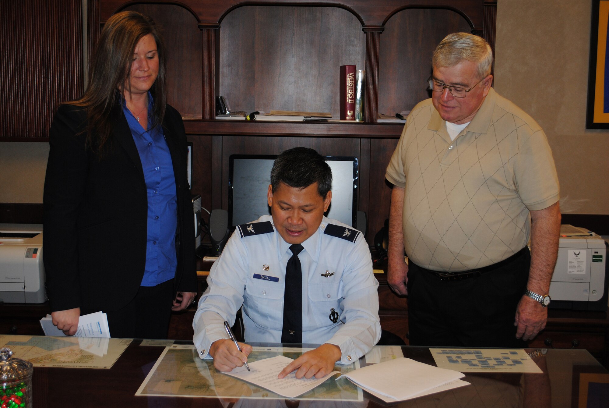 Jennifer Benski, Belfour Beatty's community manager, and Larry Boggs, Malmstrom's housing manager, watch as Col. H.B. Brual, 341st Missile Wing commander, reviews the housing lease before signing it.  (U.S. Air Force photo/Airman Cortney Paxton)