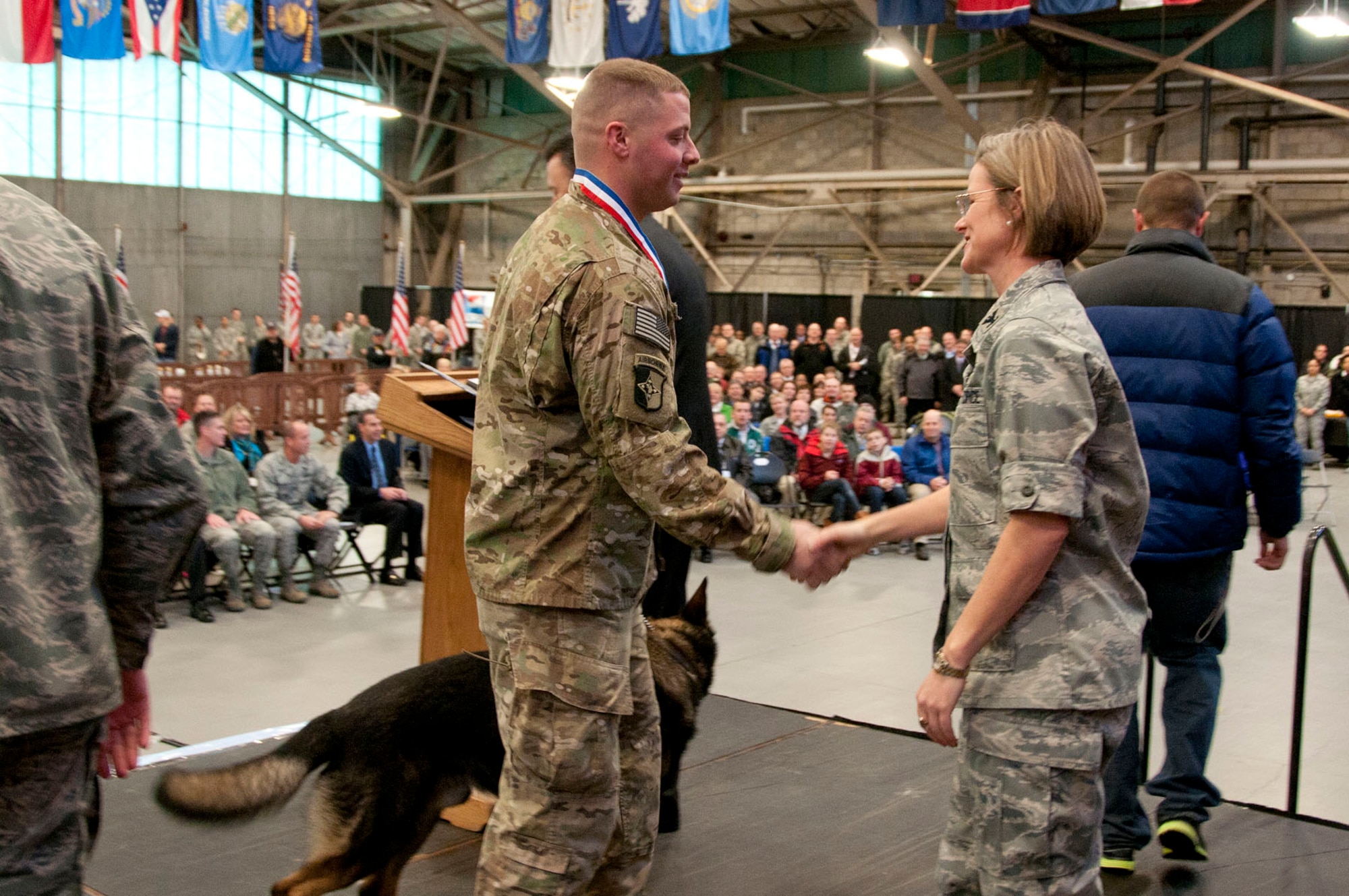 HANSCOM AIR FORCE BASE, Mass. – Senior Airman Robert R. Aikens Jr., with his K-9, Frodo, shakes hands with Col. Stacey L. Yike, 66th Air Base Group commander, during a homecoming celebration Jan. 12. Aikens was among 54 personnel assigned to the base that have returned from deployments during the past six months and were honored along with their families during the Heroes Homecoming event. (U.S. Air Force photo by Mark Wyatt)