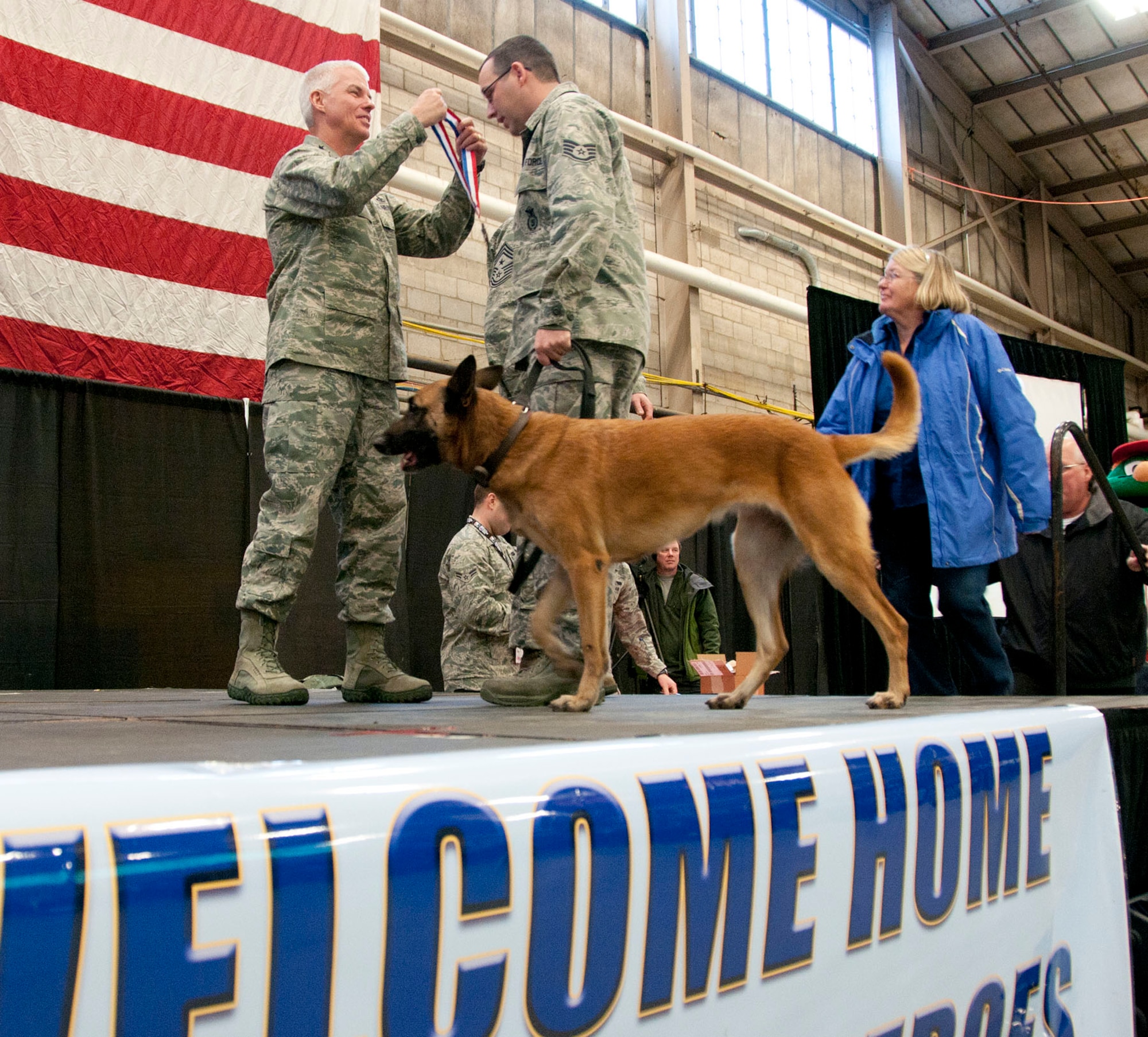 HANSCOM AIR FORCE BASE, Mass. -- Lt. Gen. CR Davis, Electronic Systems Center commander, places a medallion around the neck of Staff Sgt. Richard Crotty with his military working dog, Danita, during a homecoming celebration Jan. 12. Crotty, a MWD handler from the 66th Security Forces Squadron, returned from his deployment with Danita during the past six months and was honored along with his family during the Heroes Homecoming event. (U.S. Air Force photo by Mark Wyatt)