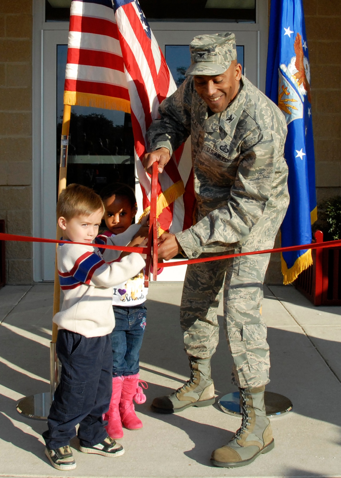 Col. Antonio Douglas, the 96th Air Base Wing vice-commander, is joined by Levi Howard and Kayla Watkins in cutting the ribbon at the new Child Development Center Jan. 13 at Eglin Air Force Base, Fla.  (U.S. Air Force photo/Kevin Gaddie)