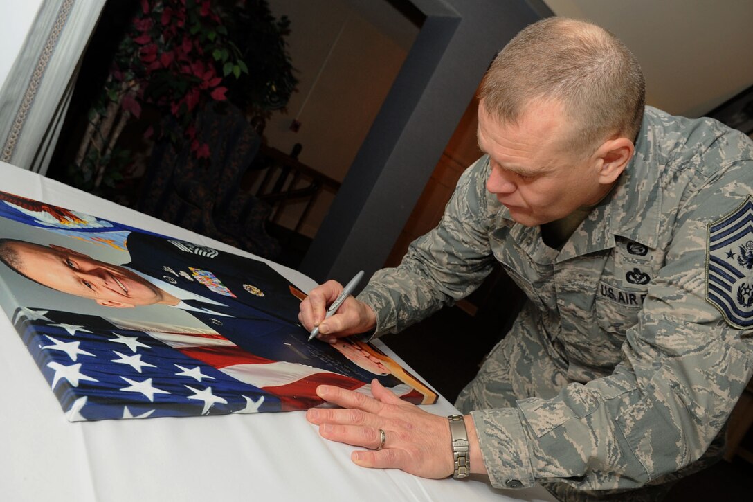 Chief Master Sgt. of the Air Force James Roy signs his portrait at the Langley Club during a visit to Langley Air Force Base, Va., Jan. 11, 2012. Portraits of previous chief master sergeants hang on the walls of the Langley Club, enshrining chiefs who made a significant and lasting impact during their service.   (U.S. Air Force photo by Airman 1st Class Racheal Watson/Released) 