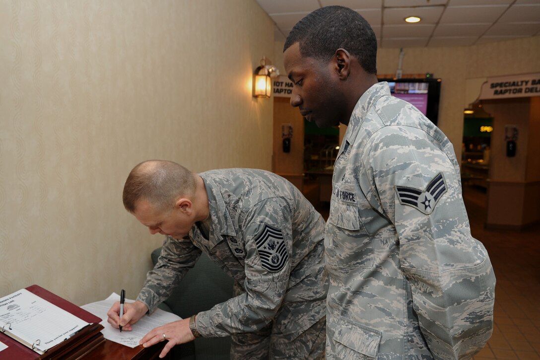 Chief Master Sgt. of the Air Force James Roy signs a Professional Development Guide for Senior Airman Derrick James, 633rd Logistics Readiness Squadron traffic management journeyman, during a visit to Langley Air Force Base, Va., Jan. 11, 2012. Chief Roy visited with Team Langley’s junior enlisted council to discuss readiness, focus on training and staying motivated. (U.S. Air Force photo by Airman 1st Class Racheal Watson/Released) 