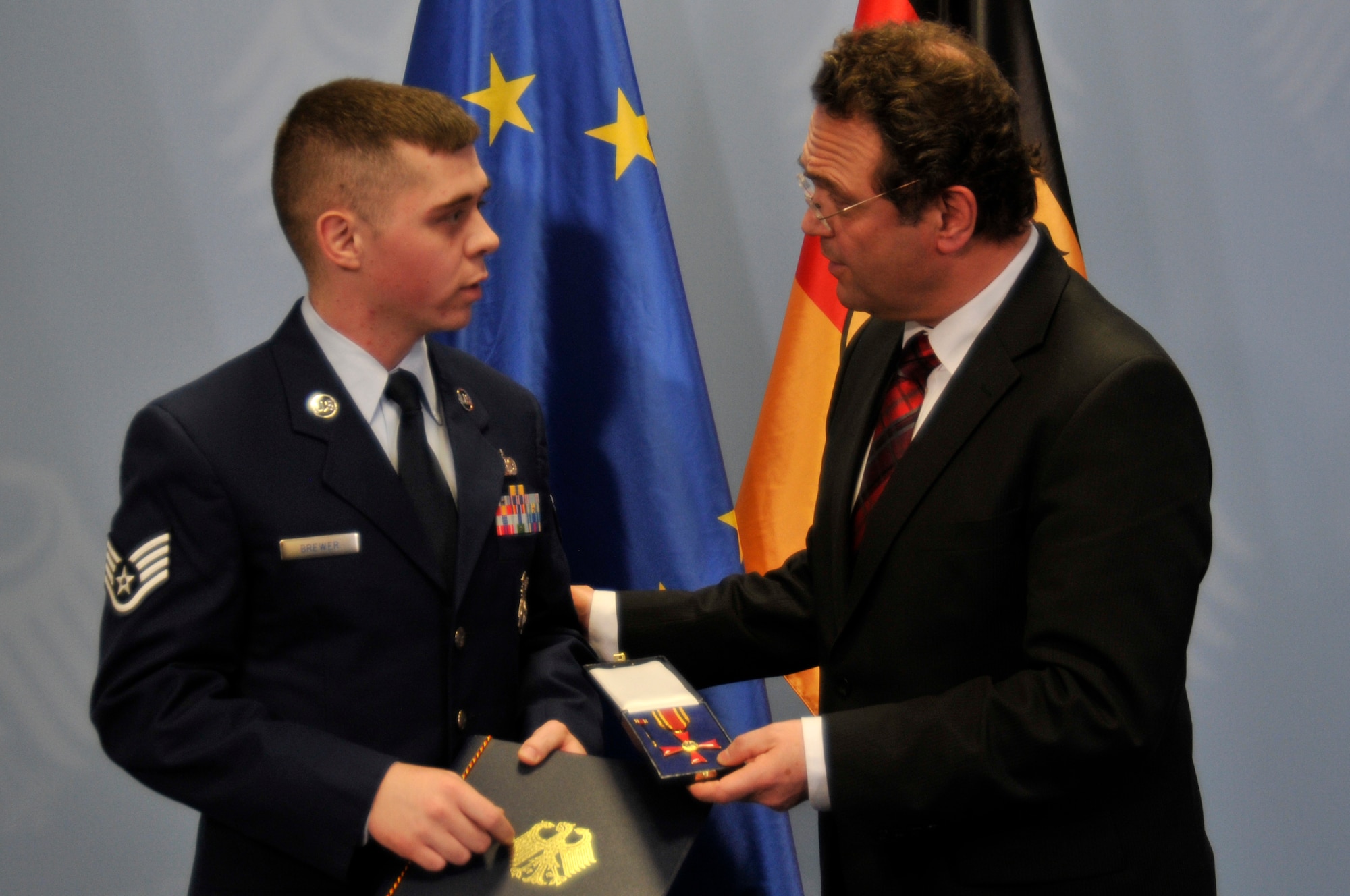 BERLIN -- Staff Sgt. Trevor Brewer, 48th Security Forces NCO in charge of vehicles, receives the Order of Merit of the Federal Republic of Germany in a ceremony here Jan. 16, 2012. The award was presented by German Interior Minister Dr. Hans-Peter Friedrich in honor of Brewer's actions during the March 2, 2011, shootings at Frankfurt International Airport in which two Airmen were killed and two others wounded. The Order of Merit is the highest tribute the Federal Republic of Germany can pay to individuals for services to the nation. (U.S. Air Force photo by Staff Sgt. David Dobrydney)