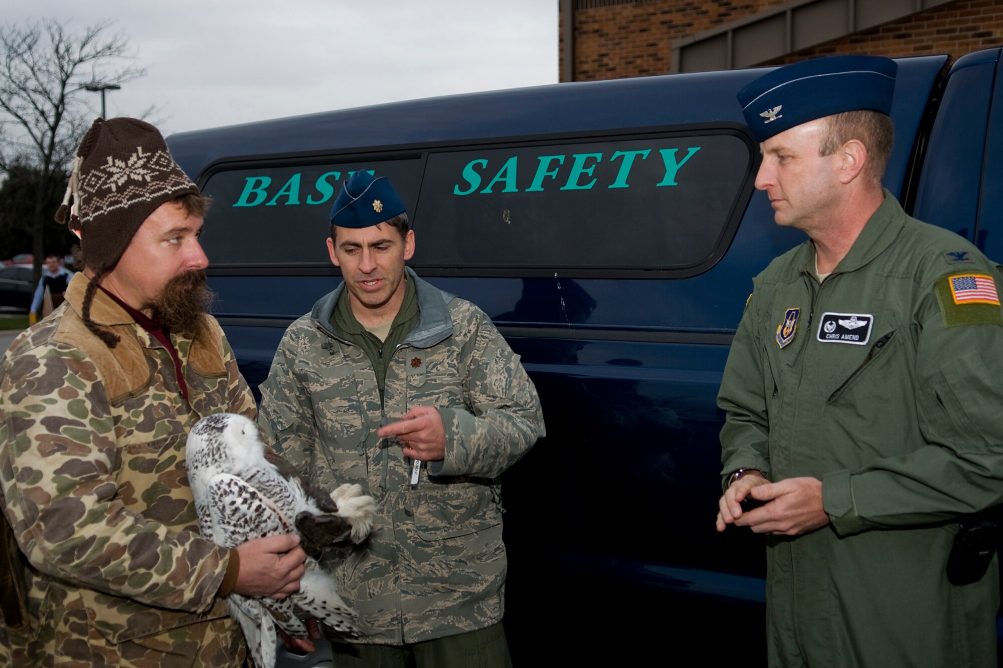 GRISSOM AIR RESERVE BASE, Ind. -- Adam Speicher, left, and Maj. Douglas Perry show Col. Chris Amend a snowy owl captured at Grissom Dec. 8. Speicher, a local falconer, helped Perry, the 434th Air Refueling Wing chief of safety, capture the bird on the Grissom airfield. Amend, the 434th Operations Group commander, named the bird Hedwig after famed literary character Harry Potter?s snowy owl. (U.S. Air Force photo/Tech. Sgt. Mark Orders-Woempner)
