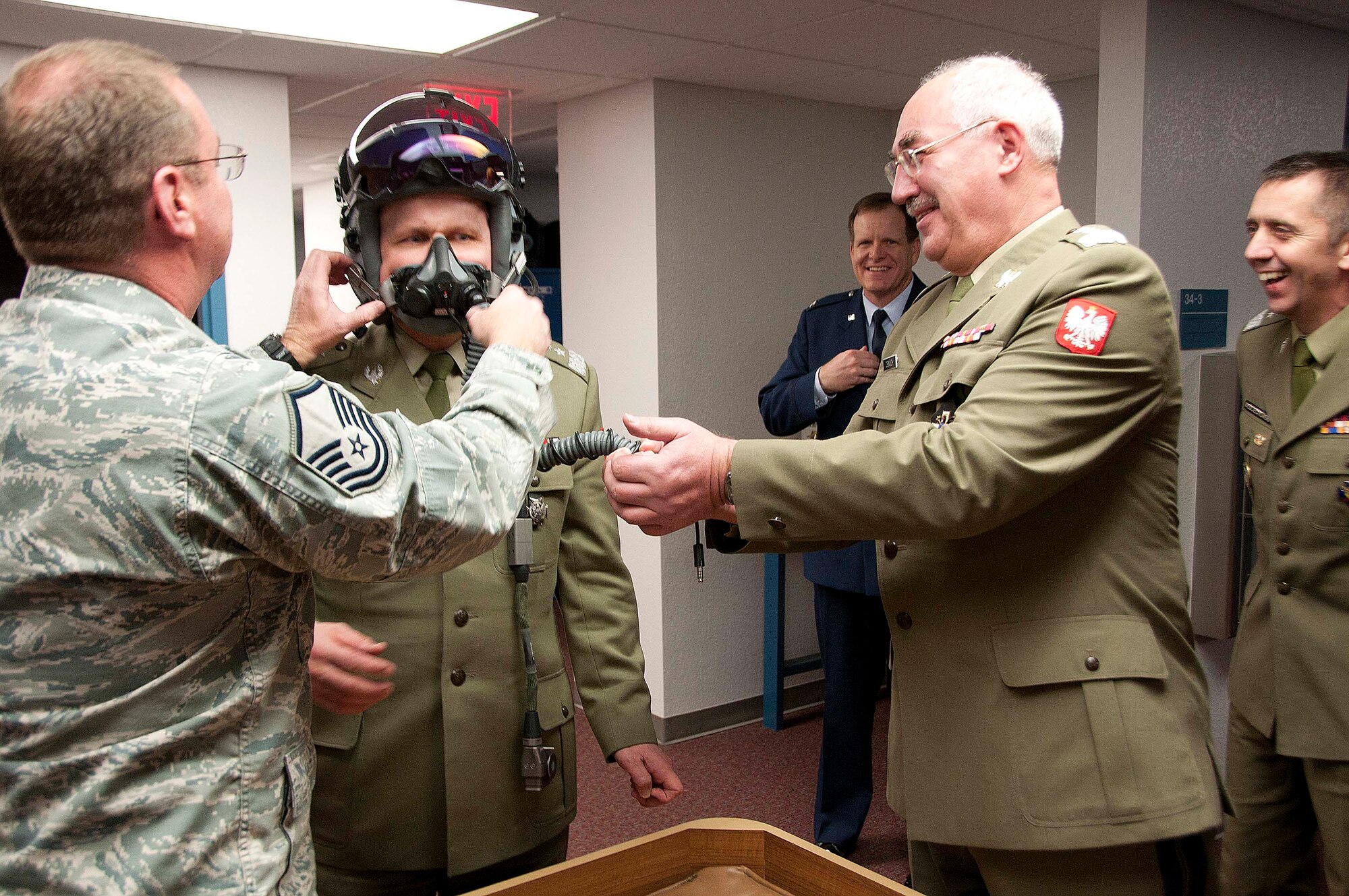 Polish Army Maj. Gen. Andrzej Falkowski, the Polish Defense Attaché to Washington D.C., tries on an F-16 pilot’s helmet equipped with the joint helmet-mounted cueing system with help from Master Sgt. Don Lauver while Polish Army Gen. Mieczyslaw Cieniuch (right), Chief of the General Staff of the Polish Armed Forces, observes Jan. 12. (U.S. Air Force photo/Master Sgt. Dave Neve)