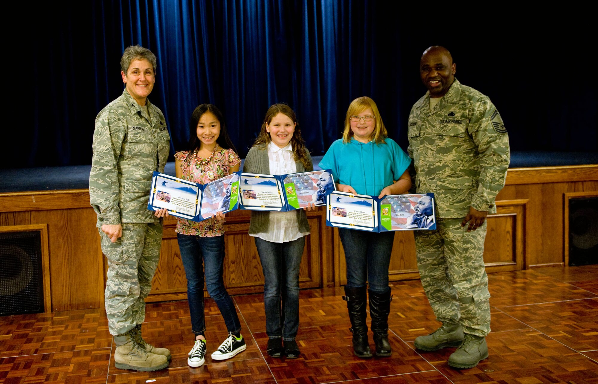 YOKOTA AIR BASE, Japan -- (Left), Col. Darlene Sanders, 374th Maintenance Group commander, and Senior Master Sgt. Tramell Jackson, (right), 374th Maintenance Operations Squadron quality assurance attendant,  pose for a picture with the poem contest winners during the annual Martin Luther King Jr. event held at Yokota Air Base, Japan, Jan. 13, 2012. Yokota Middle School students participated in a poem writing contest and the winners recited their poems at the event and received a certificate of appreciation. (U.S. Air Force photo/Airman 1st Class Krystal M. Garrett) 