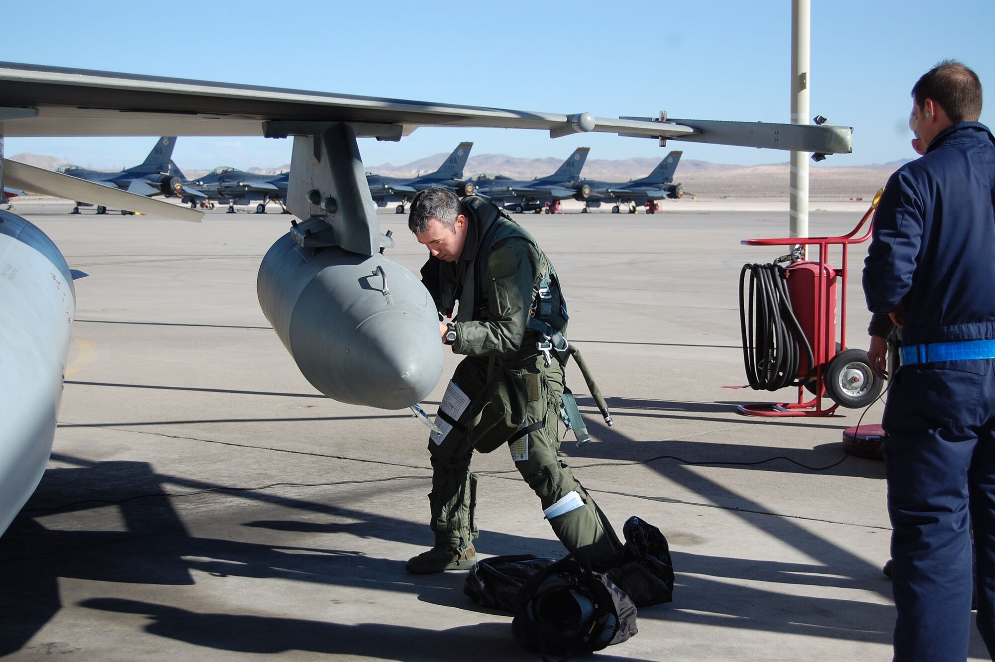 NELLIS AIR FORCE BASE, Nev. -- (left) Maj. Joshua Spear, 706th Fighter Squadron, conducts a pre-flight inspection on an F-16 Aggressor aircraft here Jan. 7. Spear traveled to Tyndall Air Force Base, Fla., to augment the 43rd Fighter Squadron's air combat training there. (U.S. Air Force photo/Capt. Jessica Martin)