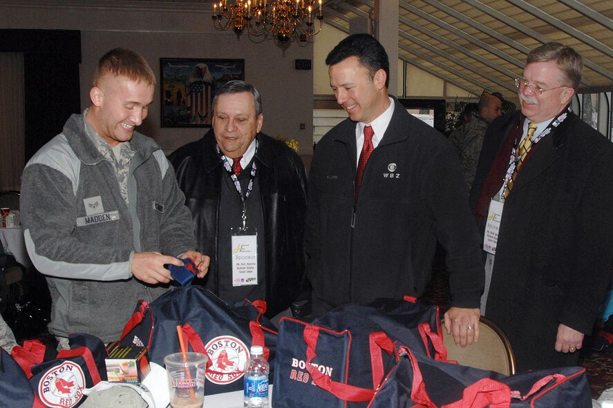 HANSCOM AIR FORCE BASE, Mass. -- Senior Airman Kyle Madden (left), from the 66th Security Forces Squadron, is all smiles as he shows Paul Marotta, Hanscom Federal Credit Union chairman; Jonathan Elias, WBZ-TV anchor; and David Spraque, Hanscom Federal Credit Union CEO, items he recieved from donations made to Airmen returning from deployments. Madden was one of 54 Airmen who have returned home from a deployment in the past six months honored during the Heroes Homecoming celebration Jan. 12. (U.S. Air Force photo by Linda LaBonte Britt) 